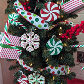 A 3D printed peppermint swirl ornament with red and white sections, lying on a dark wood grain surface. A set of three red and white candy-style Christmas tree ornaments with hanging loops. Close-up showing the 3D printed texture of a red and white peppermint ornament.