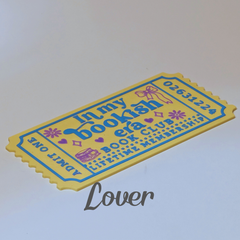 A yellow and blue bookish ticket-shaped mat or plaque with decorative text reading 'In my bookish era book club lifetime membership' and 'Admit one', shown on a plain light background with a 'Lover' watermark.