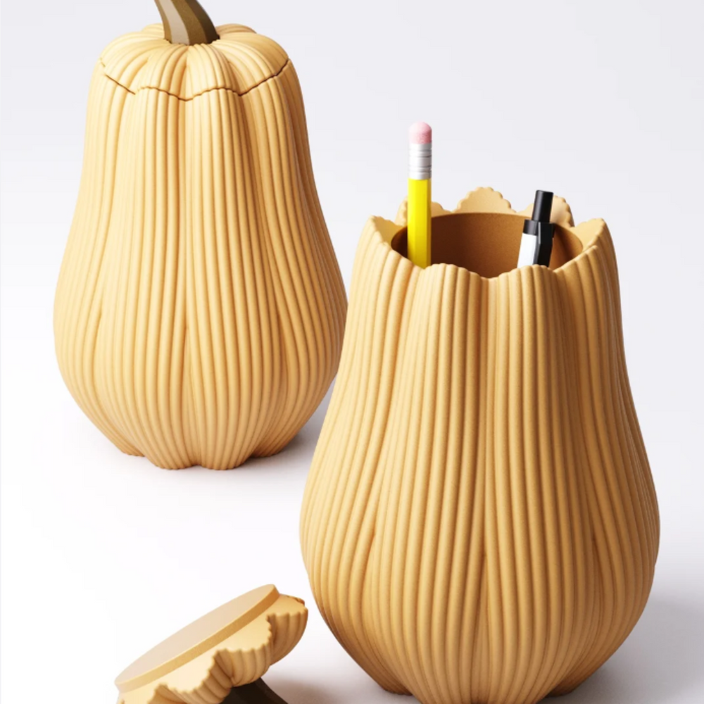 A tall, beige 3D printed pumpkin-shaped storage container with a vertical textured pattern, with its lid placed next to it on a white background.
A modern, pumpkin-shaped pen pot in a warm beige colour, holding a yellow pencil and a black pen.
Close-up of the elegant, vertically ribbed texture on a modern, 3D printed pumpkin storage container.