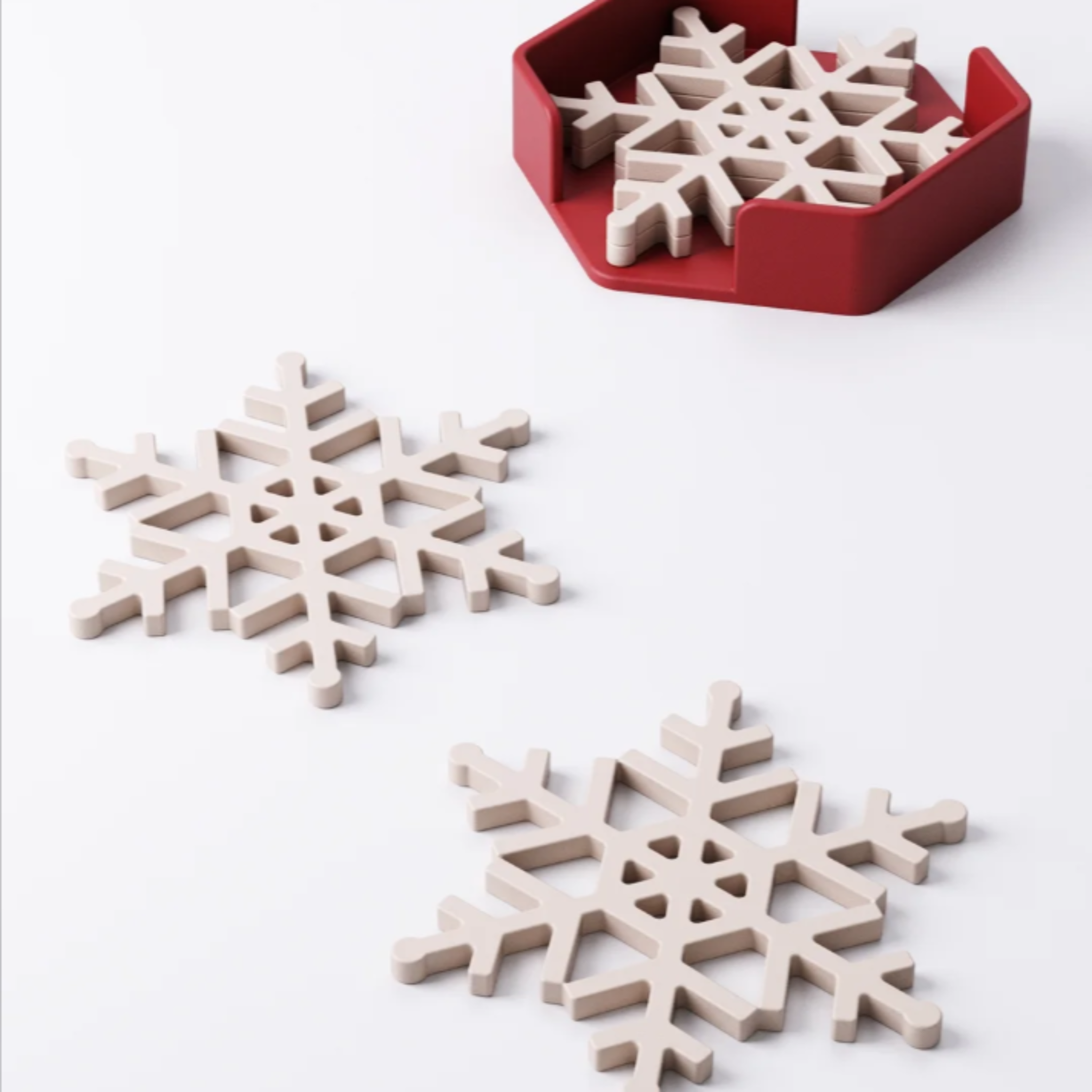 A set of four white snowflake-shaped coasters stacked neatly inside a modern red hexagonal holder on a white background.
A white snowflake coaster on a dark wood table, with a festive red mug of hot chocolate sitting on it.
A stack of white snowflake coasters next to two holder options, one red and one green.
