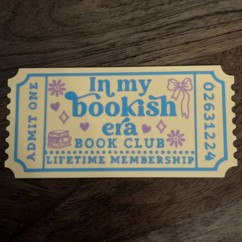 In My Bookish Era ticket bookmark photographed on hardback novels with cream and yellow design